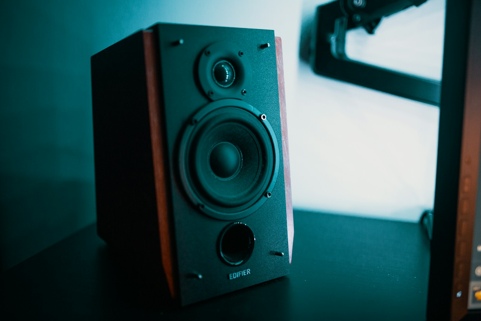 Handcrafted walnut audiophile studio monitor speakers next to vinyl turntable